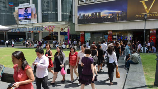 Pedestrians walk down a street in downtown financial district in Singapore.